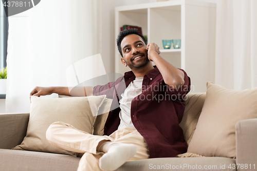 Image of happy man calling on smartphone at home