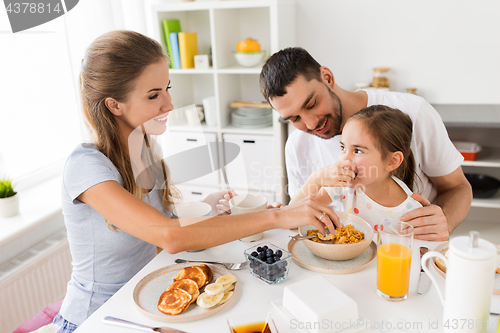 Image of happy family having breakfast at home