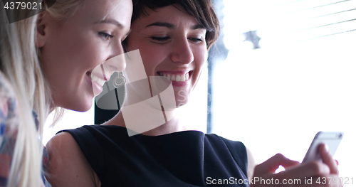 Image of two attractive business women with a cell phone discuss business