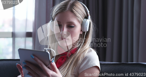 Image of Lovely Blond Woman Listening To Music while resting on couch