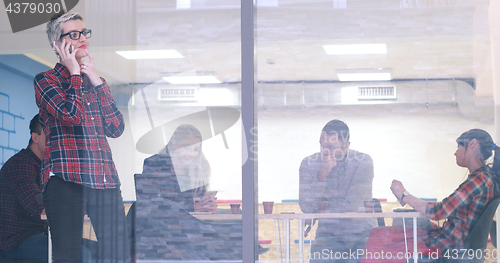 Image of Business Woman Looking Through A Window And using On A Cell Phon