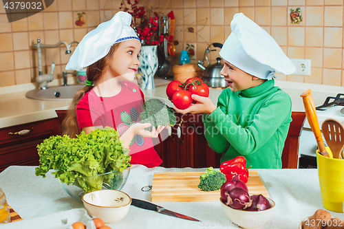 Image of happy family funny kids are preparing the a fresh vegetable salad in the kitchen