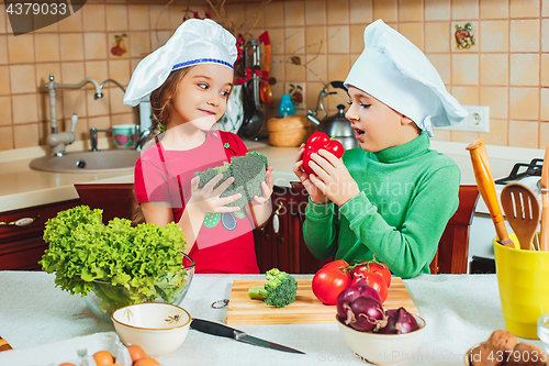 Image of happy family funny kids are preparing the a fresh vegetable salad in the kitchen