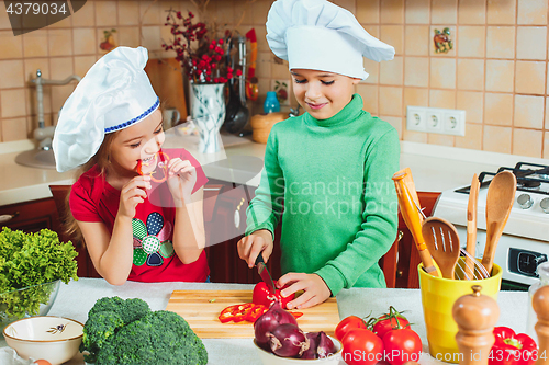 Image of happy family funny kids are preparing the a fresh vegetable salad in the kitchen