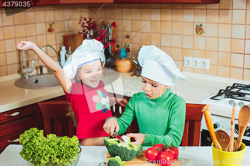 Image of happy family funny kids are preparing the a fresh vegetable salad in the kitchen