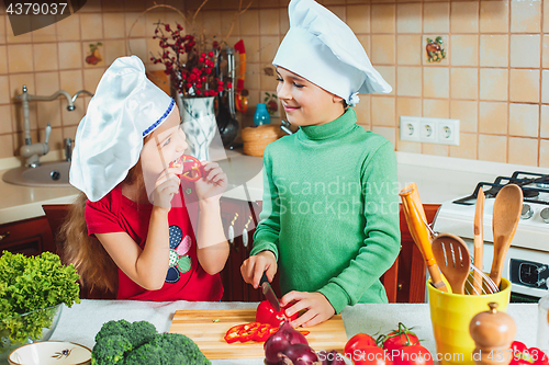 Image of happy family funny kids are preparing the a fresh vegetable salad in the kitchen