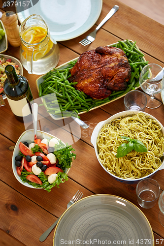 Image of pasta, vegetable salad and roast chicken on table