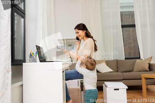 Image of happy mother with baby and papers working at home