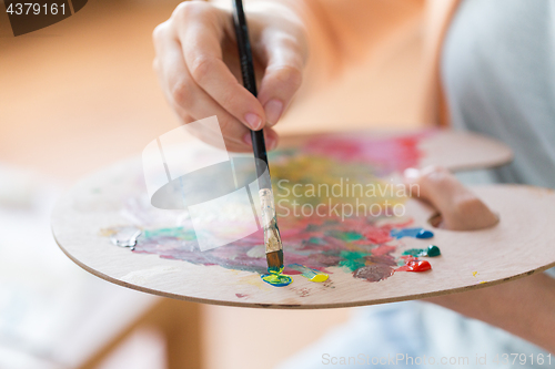 Image of artist with palette and brush painting at studio