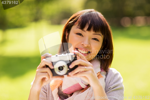 Image of happy young asian woman with film camera outdoors