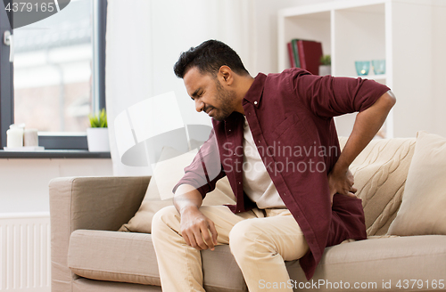 Image of unhappy man suffering from backache at home