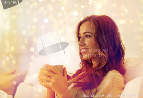 Image of happy woman with cup of coffee in bed at home