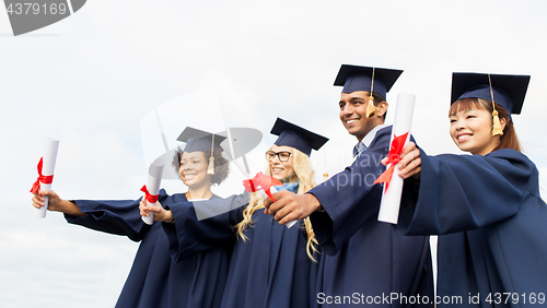 Image of happy students in mortar boards with diplomas