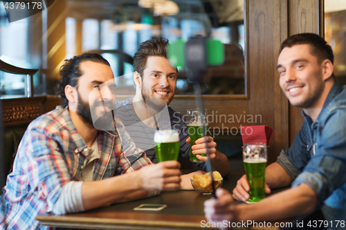 Image of friends taking selfie with green beer at pub