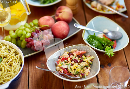Image of salad, fruits and pasta on wooden table