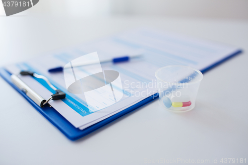 Image of clipboard with report and drugs in medical cup