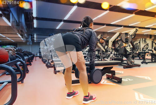 Image of young woman flexing muscles with dumbbells in gym