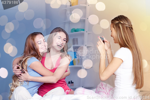 Image of teen girls with smartphone taking picture at home