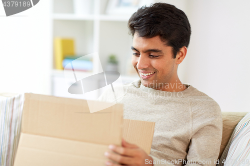 Image of happy man opening parcel box at home