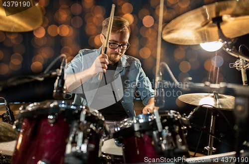 Image of musician playing drum kit at concert over lights