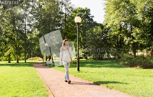 Image of happy pregnant asian woman walking at park