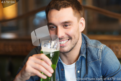 Image of close up of man drinking green beer at bar or pub