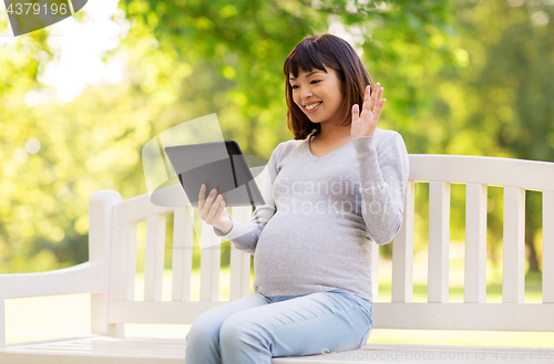 Image of happy pregnant asian woman with tablet pc at park