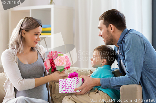 Image of family giving present to pregnant mother at home