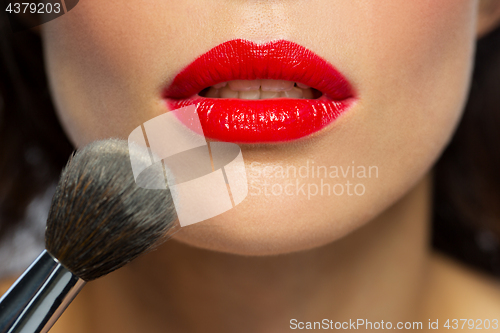 Image of face of woman with red lipstick applying powder