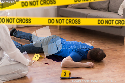 Image of criminalist collecting evidence at crime scene