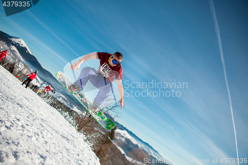 Image of Bukovel, Ukraine - December 22, 2016: Man boarder jumping on his snowboard against the backdrop of mountains, hills and forests in the distance. Bukovel, Carpathian mountains