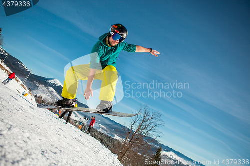 Image of Bukovel, Ukraine - December 22, 2016: Man boarder jumping on his snowboard against the backdrop of mountains, hills and forests in the distance. Bukovel, Carpathian mountains