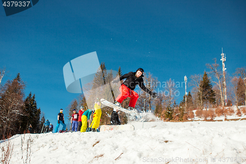 Image of Bukovel, Ukraine - December 22, 2016: Man boarder jumping on his snowboard against the backdrop of mountains, hills and forests in the distance. Bukovel, Carpathian mountains