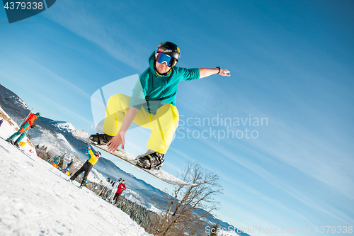 Image of Bukovel, Ukraine - December 22, 2016: Man boarder jumping on his snowboard against the backdrop of mountains, hills and forests in the distance. Bukovel, Carpathian mountains