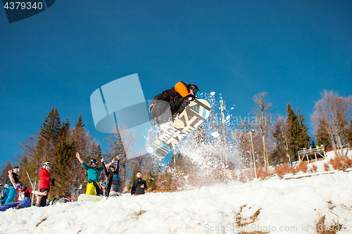 Image of Bukovel, Ukraine - December 22, 2016: Man boarder jumping on his snowboard against the backdrop of mountains, hills and forests in the distance. Bukovel, Carpathian mountains