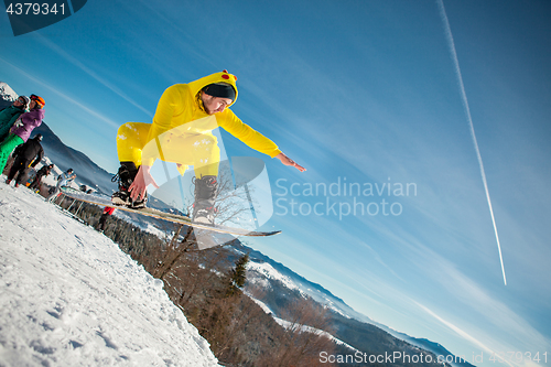 Image of Bukovel, Ukraine - December 22, 2016: Man boarder jumping on his snowboard against the backdrop of mountains, hills and forests in the distance. Bukovel, Carpathian mountains