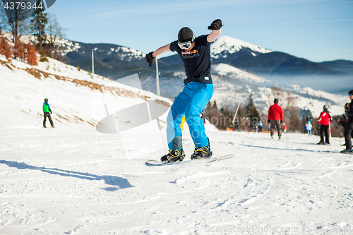 Image of Bukovel, Ukraine - December 22, 2016: Man boarder jumping on his snowboard against the backdrop of mountains, hills and forests in the distance. Bukovel, Carpathian mountains