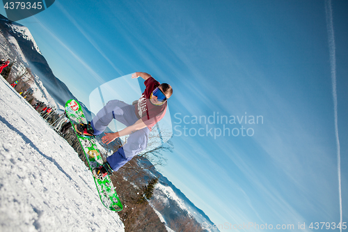 Image of Bukovel, Ukraine - December 22, 2016: Man boarder jumping on his snowboard against the backdrop of mountains, hills and forests in the distance. Bukovel, Carpathian mountains