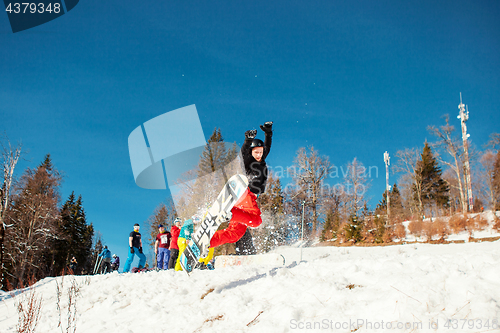 Image of Bukovel, Ukraine - December 22, 2016: Man boarder jumping on his snowboard against the backdrop of mountains, hills and forests in the distance. Bukovel, Carpathian mountains