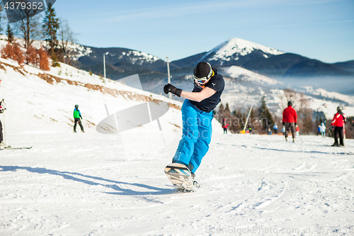 Image of Bukovel, Ukraine - December 22, 2016: Man boarder jumping on his snowboard against the backdrop of mountains, hills and forests in the distance. Bukovel, Carpathian mountains