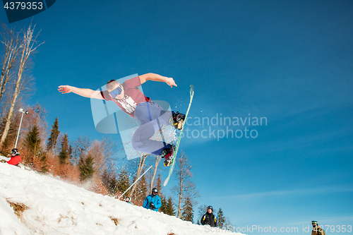 Image of Bukovel, Ukraine - December 22, 2016: Man boarder jumping on his snowboard against the backdrop of mountains, hills and forests in the distance. Bukovel, Carpathian mountains