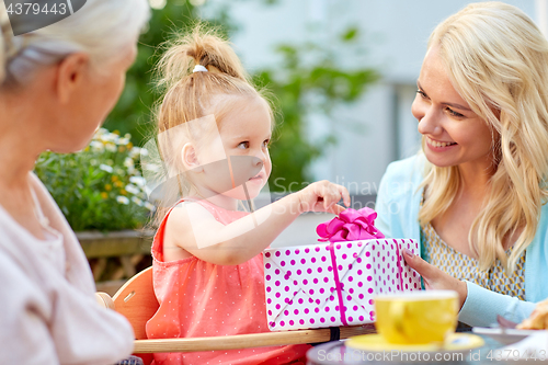 Image of happy mother giving present to daughter at cafe