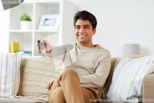 Image of man with remote control watching tv at home