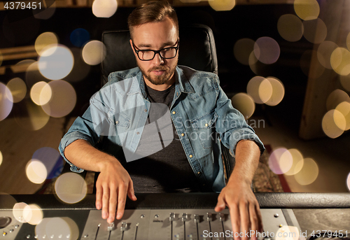 Image of man at mixing console in music recording studio