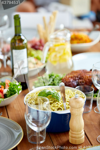 Image of pasta with basil in bowl and other food on table