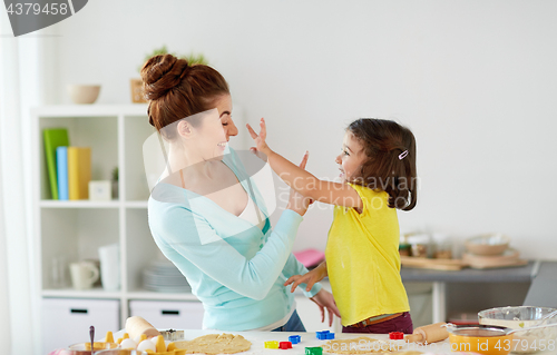 Image of happy mother and daughter making cookies at home