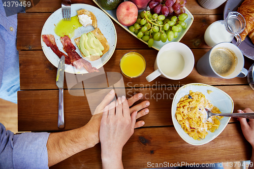 Image of couple hands on table full of food