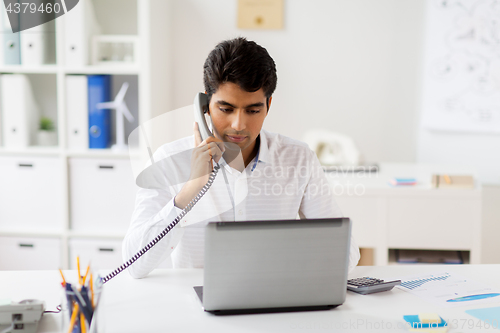 Image of businessman calling on desk phone at office