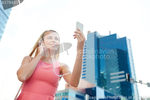 Image of happy young woman with smartphone and earphones