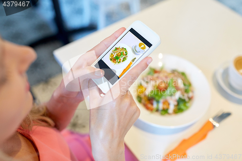 Image of woman with smartphone photographing food at cafe